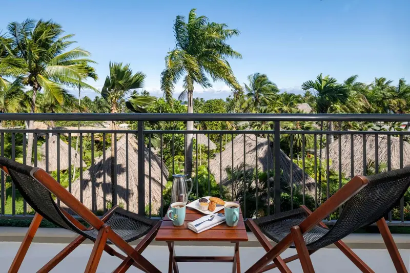 Deux fauteuils en osier sont disposés sur une terrasse avec une table servant le petit-déjeuner.