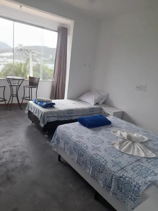 Une chambre lumineuse avec deux lits simples et une table haute près de la fenêtre.