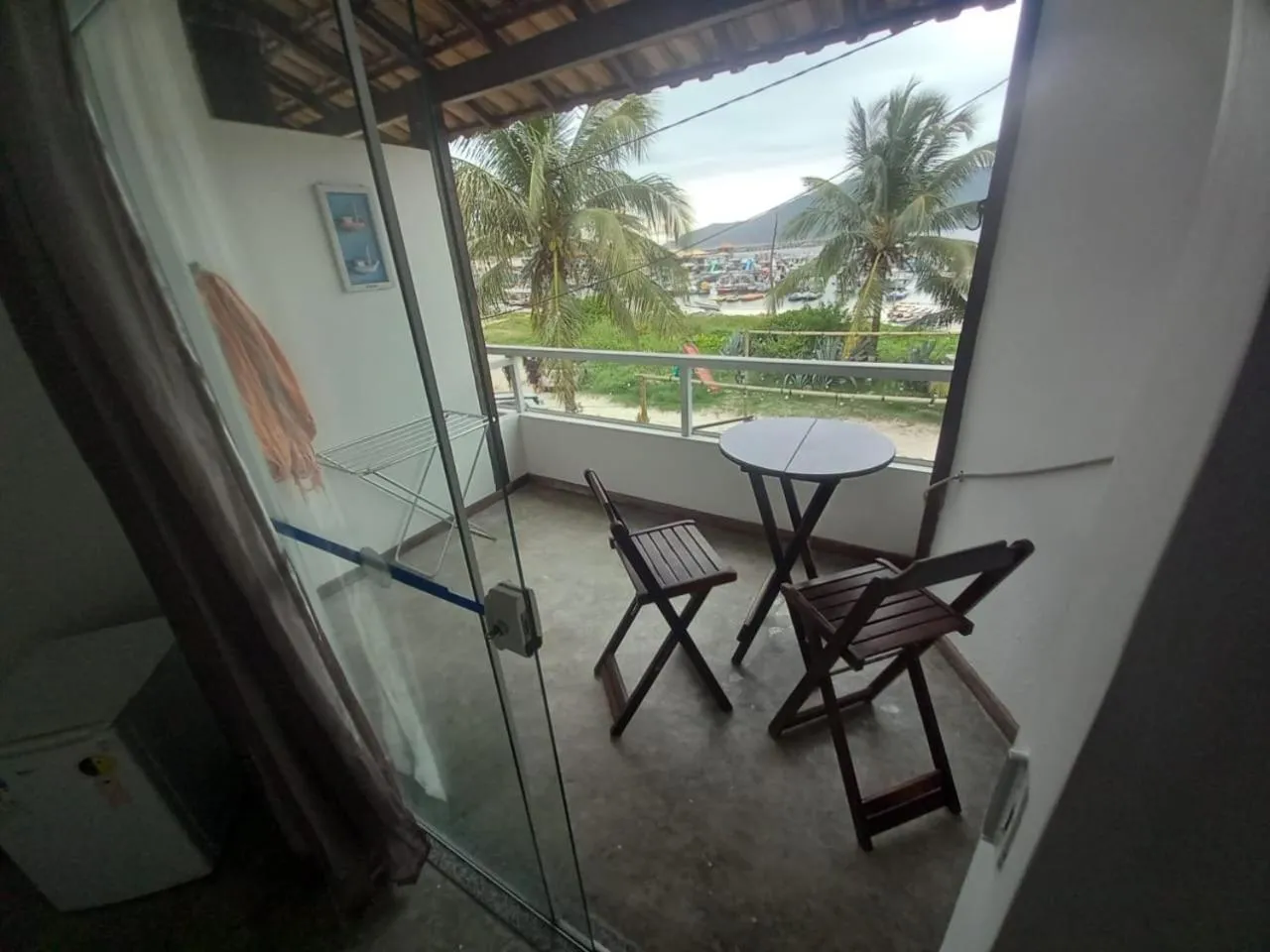 Une terrasse avec une table ronde et des chaises en bois offre une vue sur la mer et la végétation.