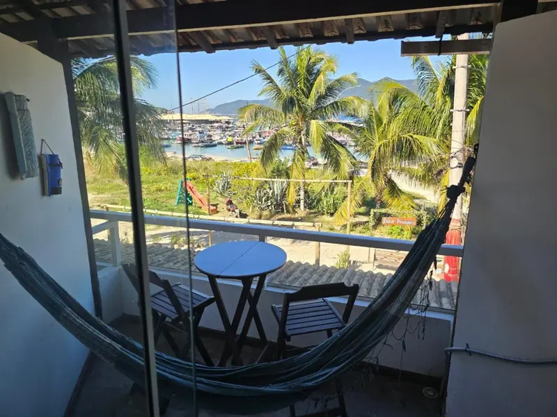Terrasse avec table et hamac donnant sur une vue de la mer et des collines.