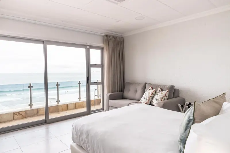 Une chambre lumineuse avec un canapé et un lit donnant sur une vue mer.
