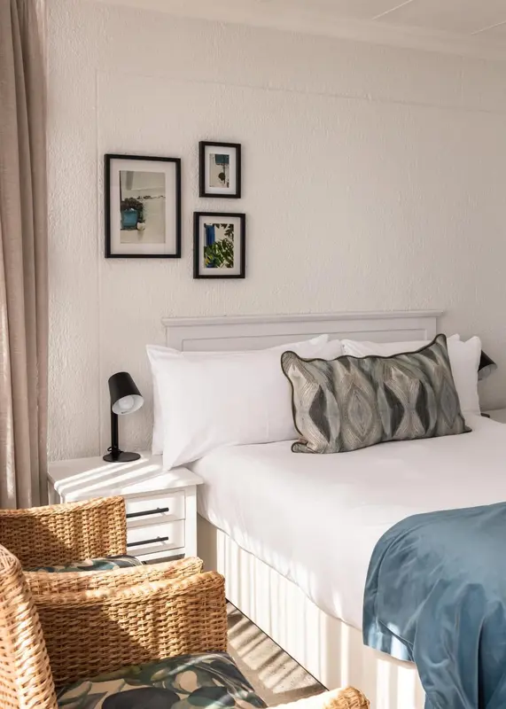 Un lit blanc avec des oreillers et un coussin décoratif dans une chambre lumineuse.