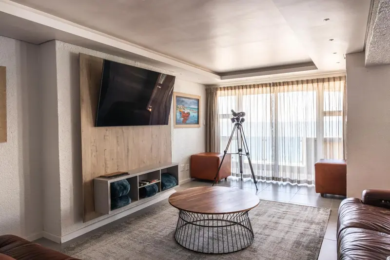 Un salon moderne avec un grand téléviseur mural et une vue sur l'océan.