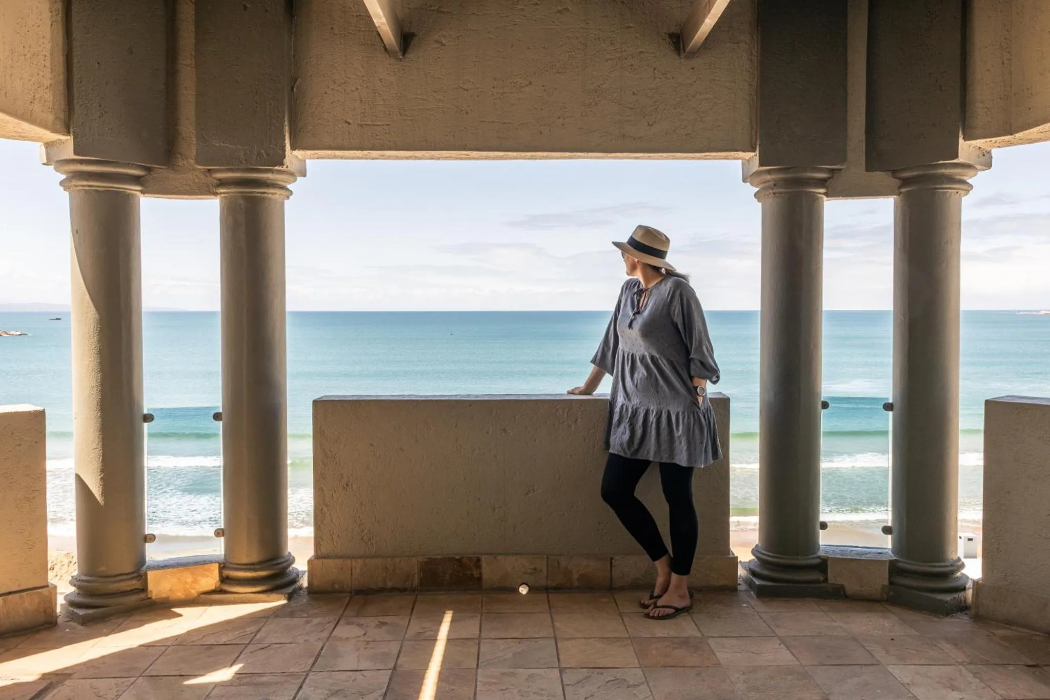 Une personne se tient sur une terrasse avec vue sur la mer.