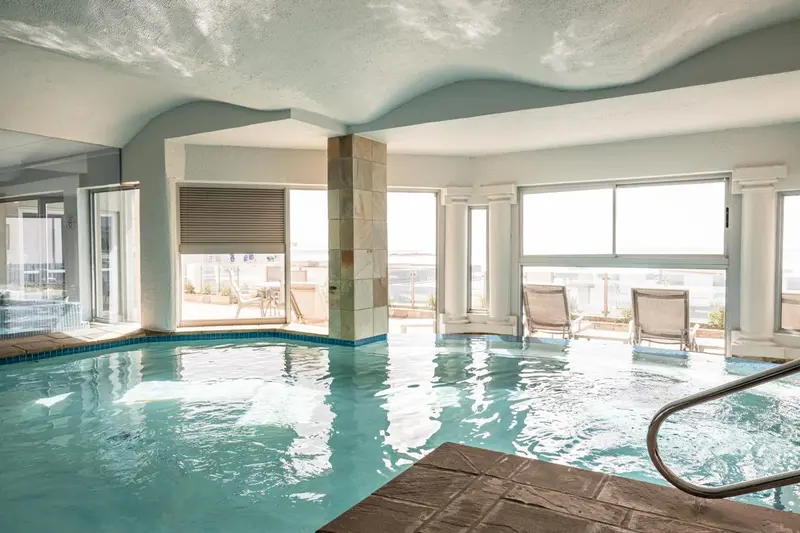 Piscine intérieure lumineuse avec vue sur l'extérieur.