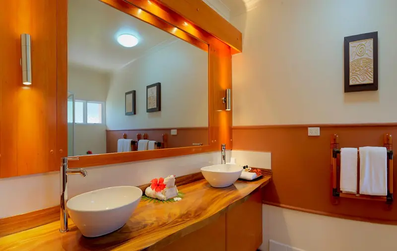 Une salle de bain lumineuse avec deux vasques sur un meuble en bois.
