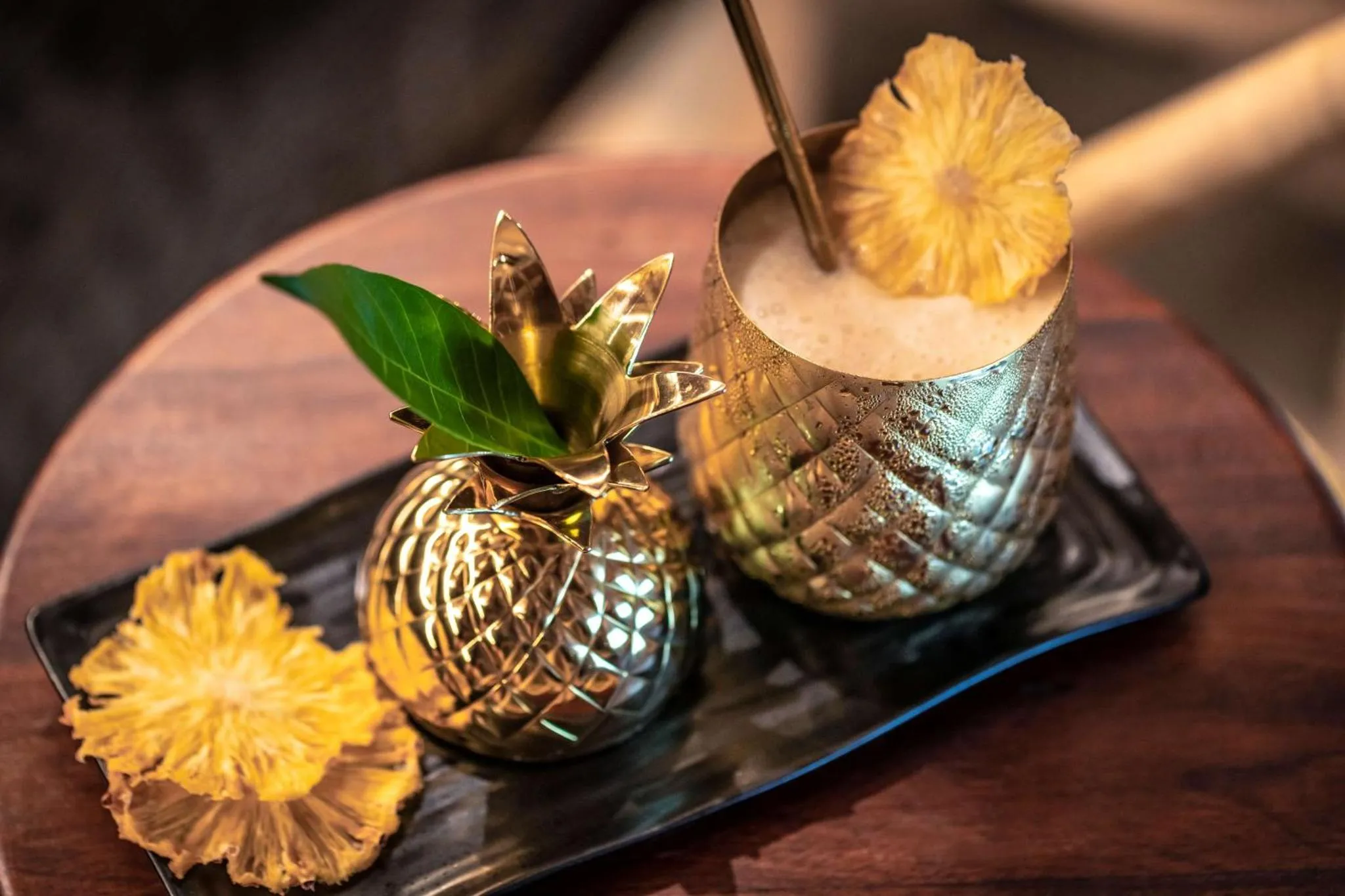 Un cocktail exotique servi dans un verre en forme d'ananas, accompagné de tranches d'agrumes.