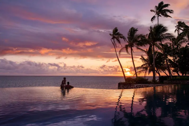 Une piscine à débordement offre une vue sur la mer au coucher du soleil.