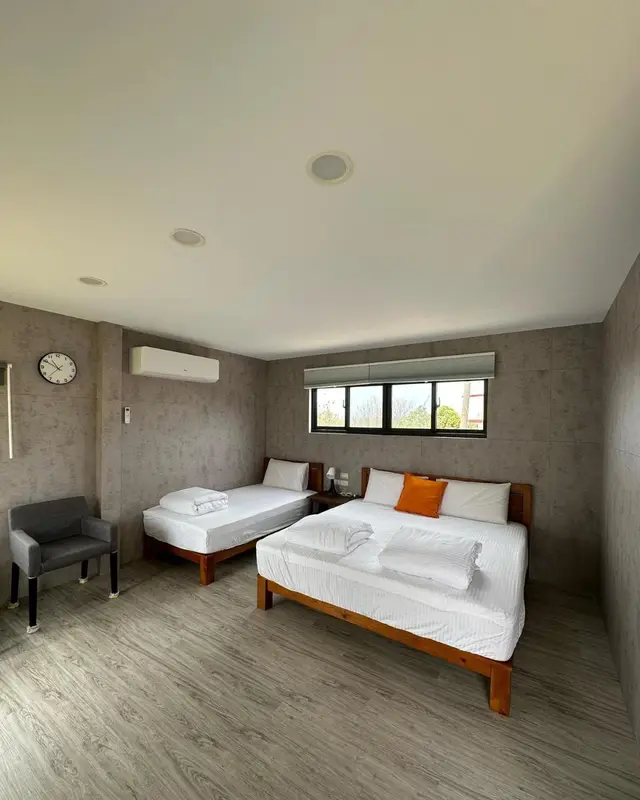 Une chambre lumineuse avec deux lits simples et un fauteuil.