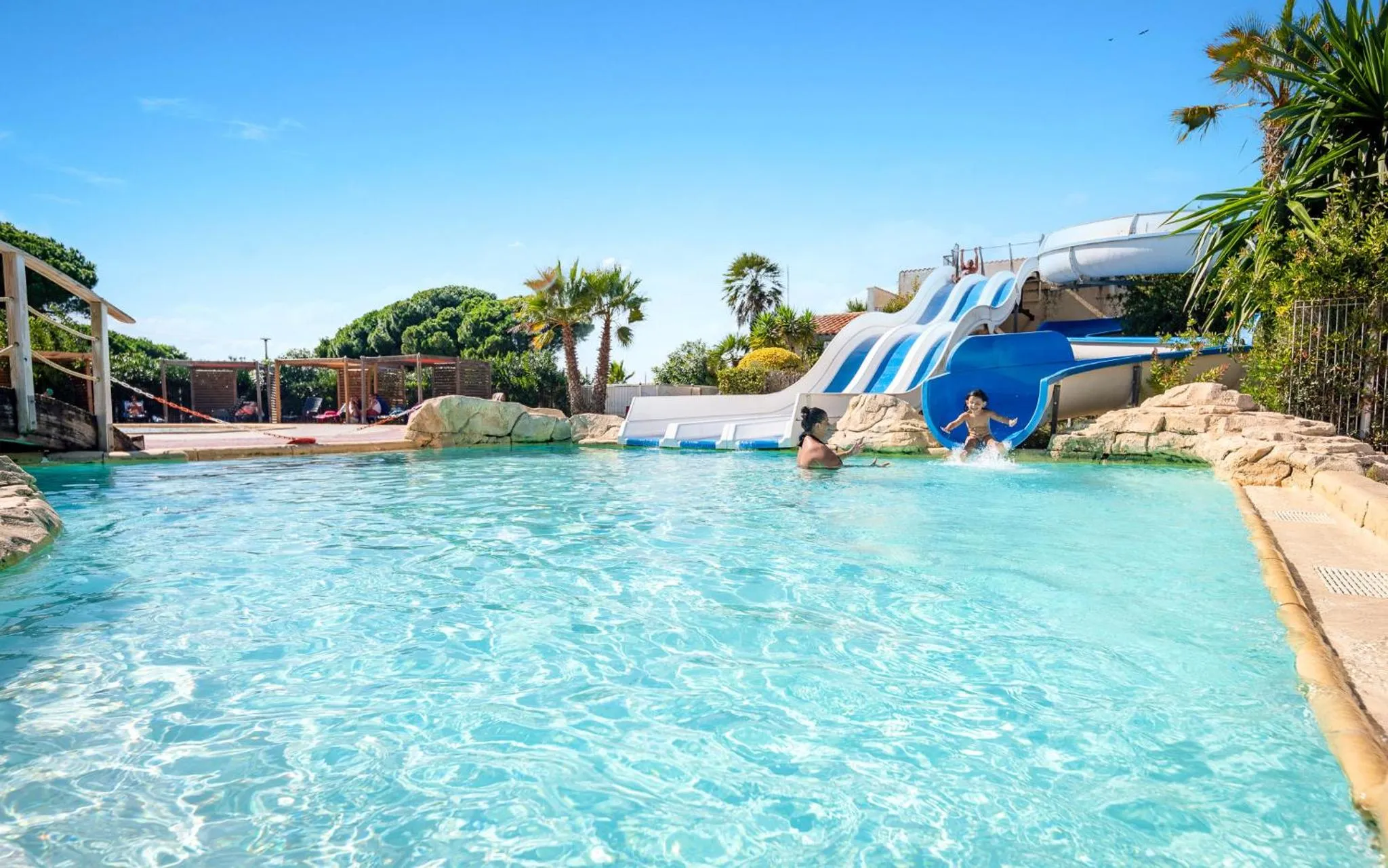 Une piscine avec toboggans et des personnes s'amusant dans l'eau.