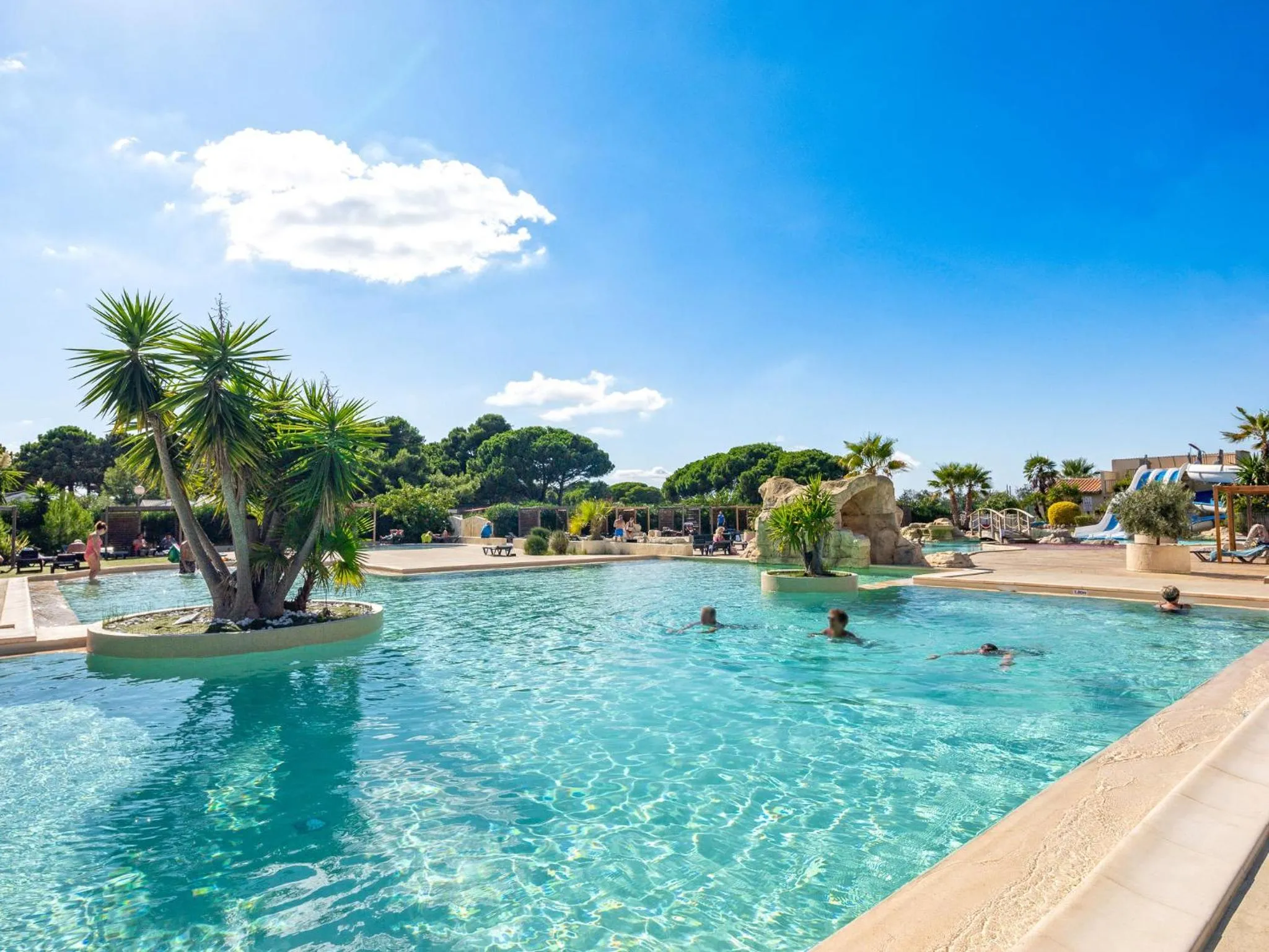 Une piscine avec des personnes se baignant sous un ciel bleu.