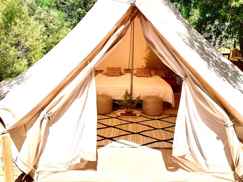 Une tente aménagée avec un lit et des coussins.