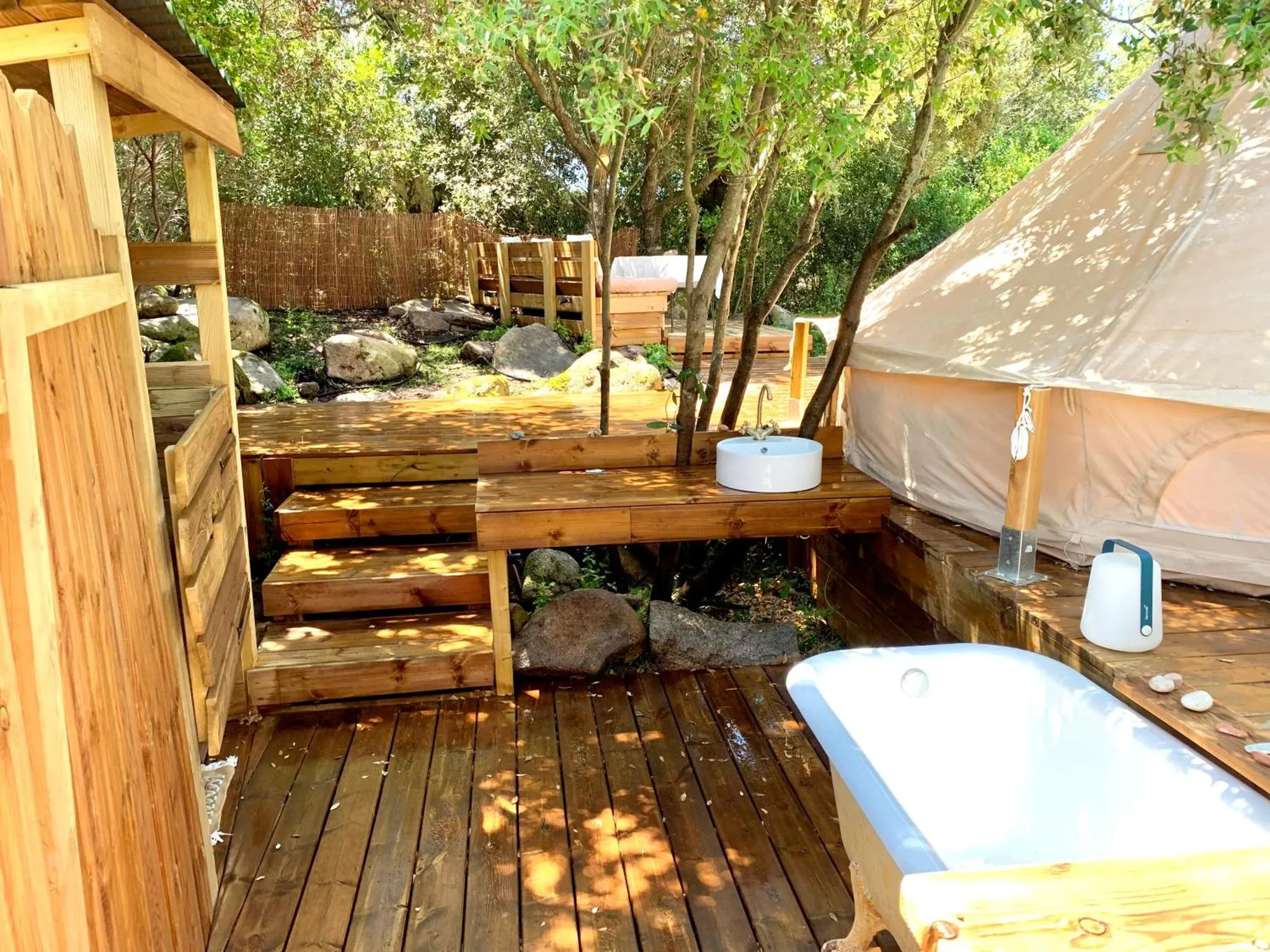 Terrasse en bois avec baignoire et lavabo extérieur.