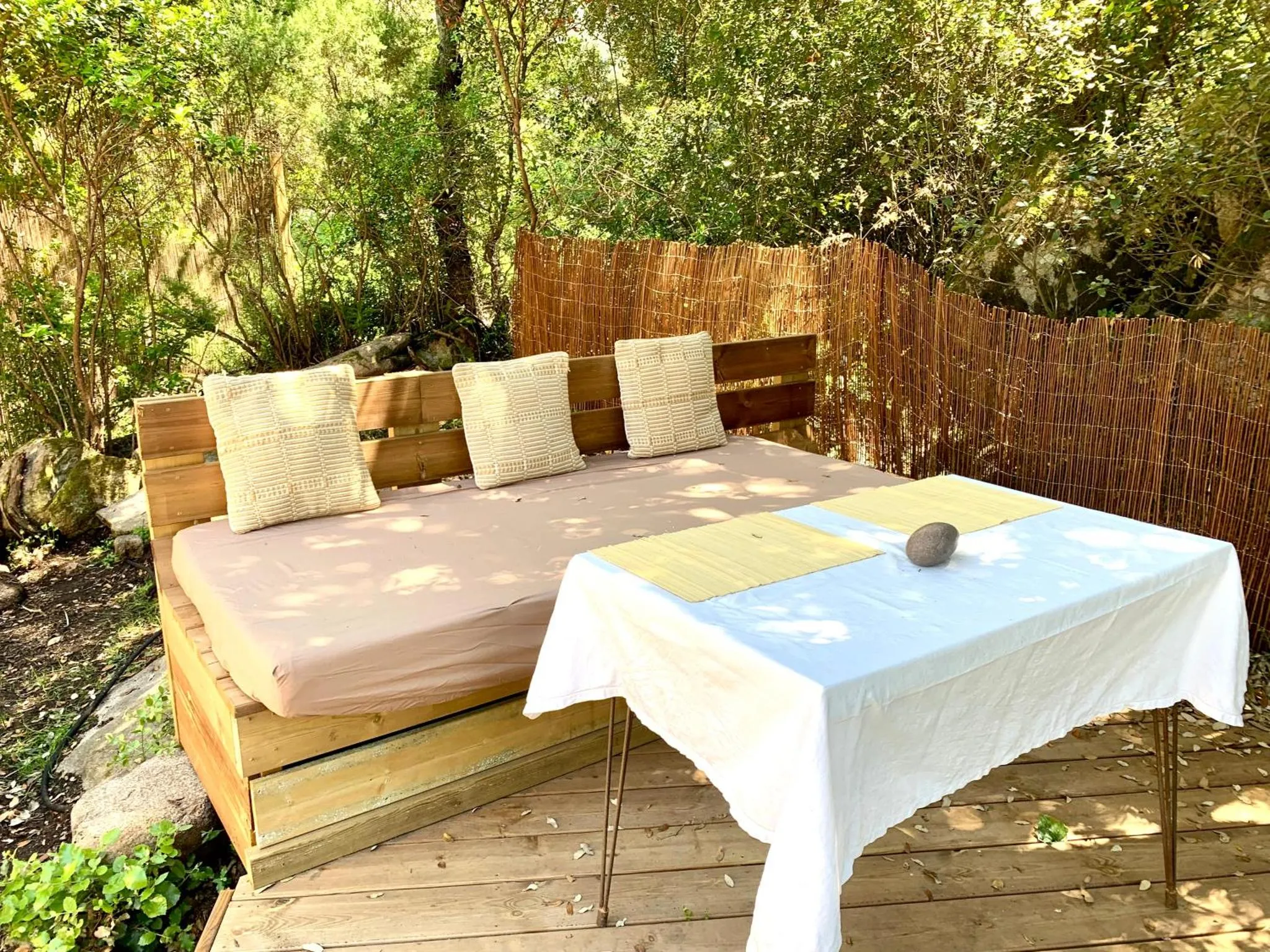 Canapé extérieur avec coussins et table basse sur une terrasse en bois.