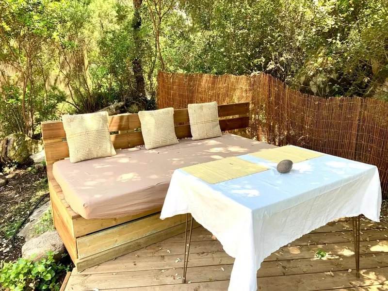 Canapé extérieur avec coussins et table basse sur une terrasse en bois.