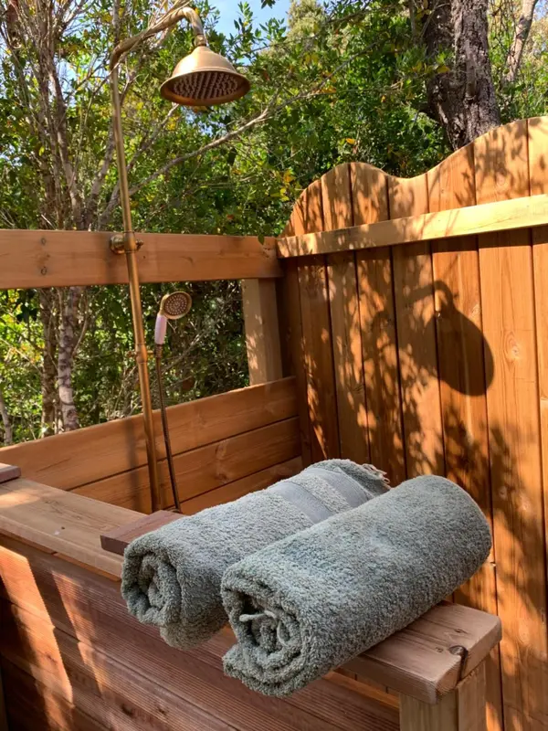 Douche extérieure en bois avec pommeau et serviettes.