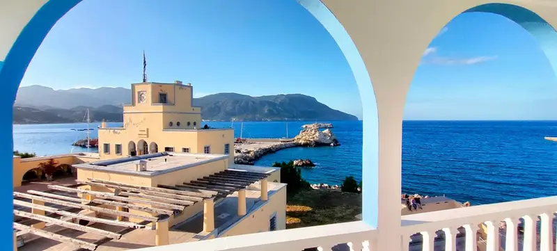 Vue sur un bâtiment blanc et une mer bleue depuis une arche.