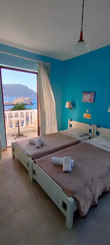 Chambre lumineuse avec deux lits simples et vue sur la mer.