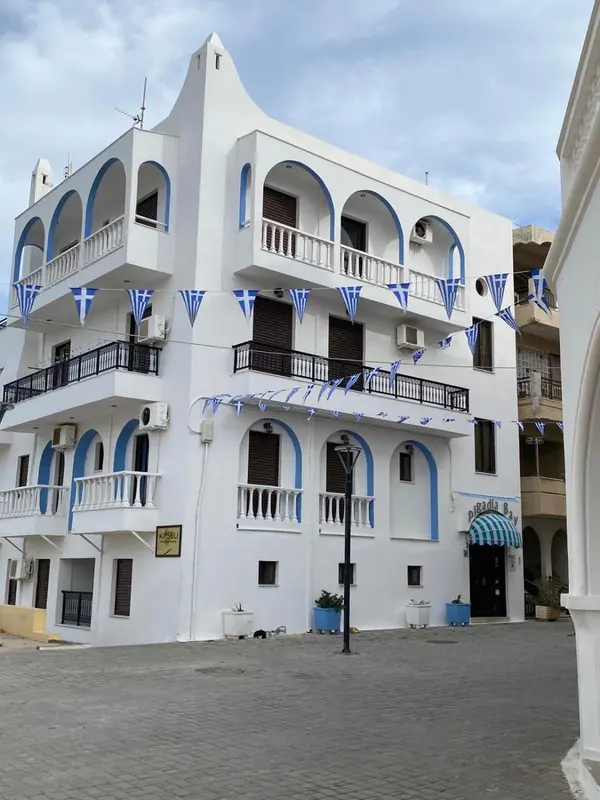 Bâtiment blanc à plusieurs étages avec des balcons et des guirlandes décoratives.