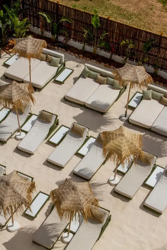 Transats et parasols de plage alignés sur une terrasse ensoleillée.