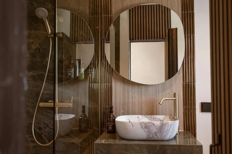 Une salle de bain moderne avec une douche à l'italienne et un lavabo sur un plan de travail en marbre.