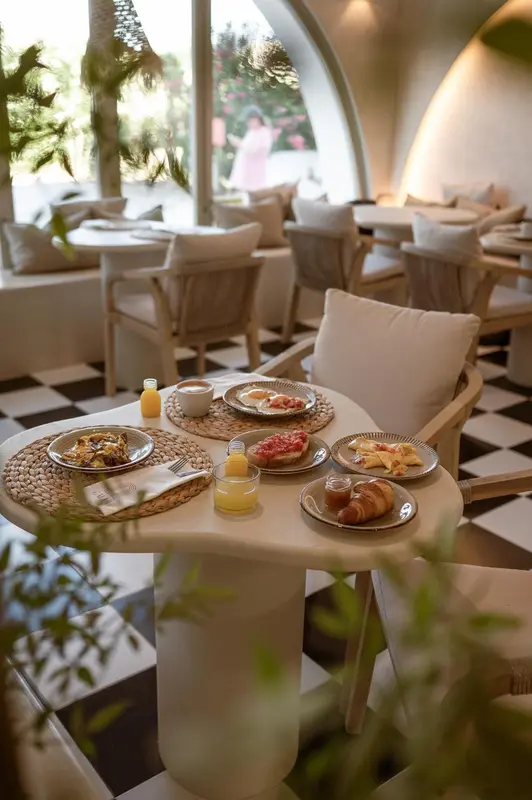 Une table ronde est dressée avec des plateaux de petit-déjeuner.