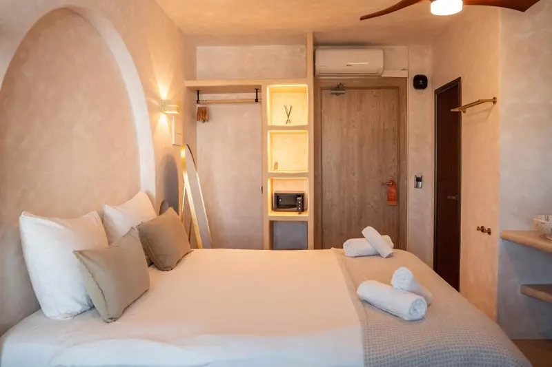 Une chambre lumineuse avec un grand lit recouvert de coussins blancs.