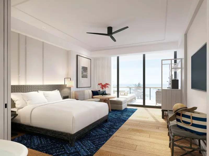 Chambre lumineuse avec un grand lit et une vue sur la mer.