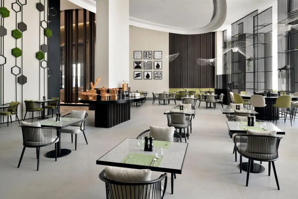 Une salle lumineuse avec des tables dressées pour un repas.