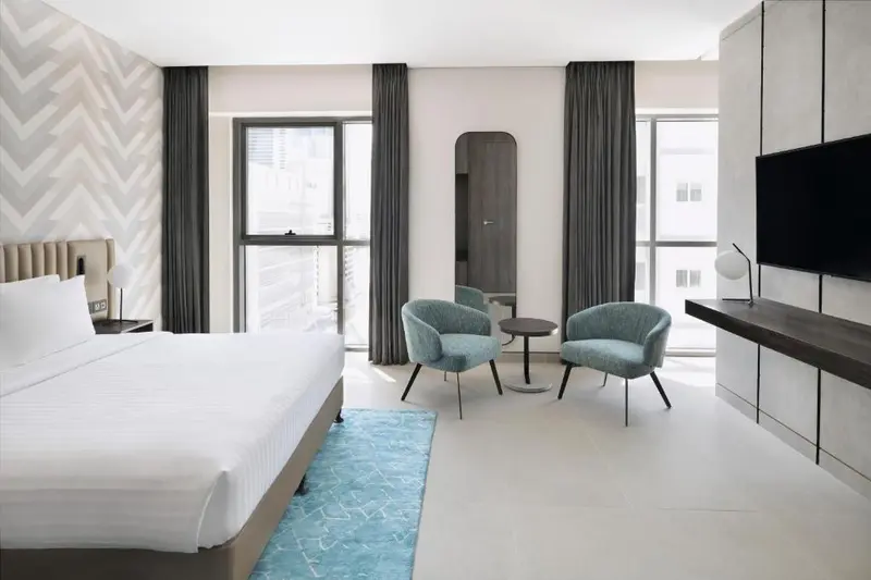 Une chambre lumineuse avec un lit et un coin salon près d'une fenêtre.