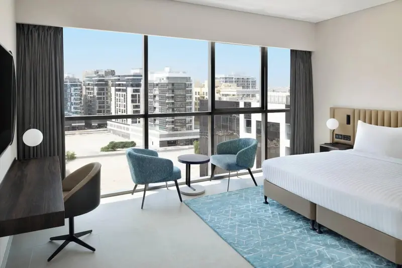 Une chambre lumineuse avec un grand lit et une vue sur la ville.
