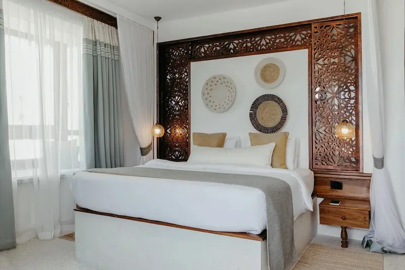 Une chambre lumineuse avec un grand lit et une décoration murale en bois.