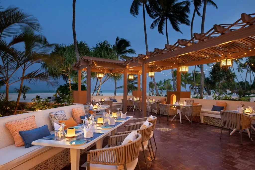 Une terrasse de restaurant éclairée aux bougies avec vue sur la mer au crépuscule.