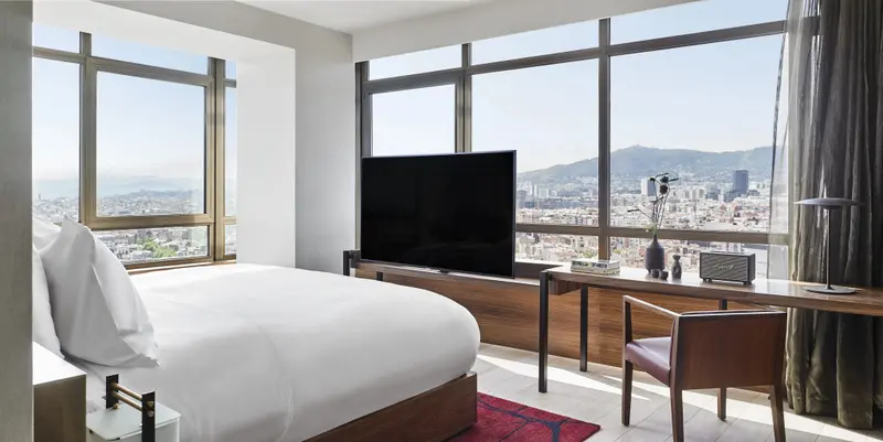 Une chambre lumineuse avec un grand lit et une vue sur la ville.