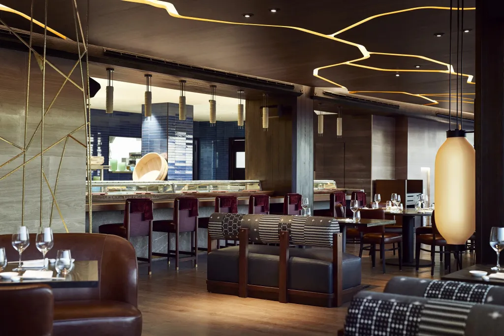 Une salle de restaurant moderne avec des tables et des luminaires suspendus.
