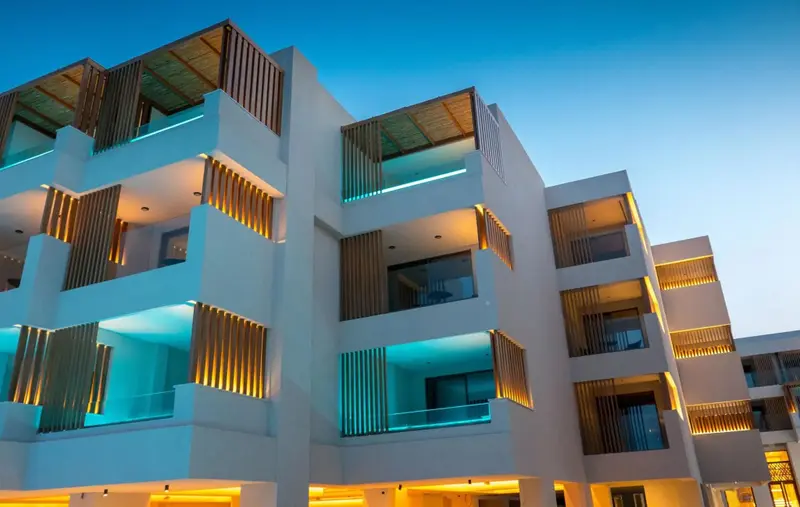 Façade moderne d'un bâtiment avec des balcons illuminés et des éléments décoratifs en bois.
