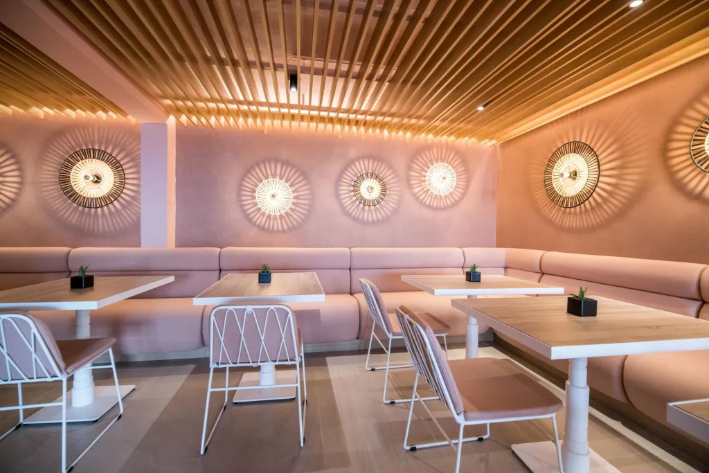 Une salle lumineuse avec des tables et des banquettes roses.