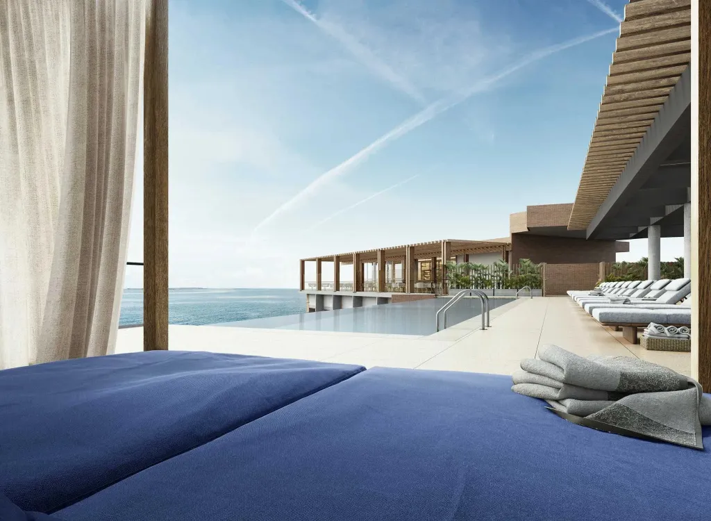 Transats bleus au bord d'une piscine à débordement avec vue sur la mer.