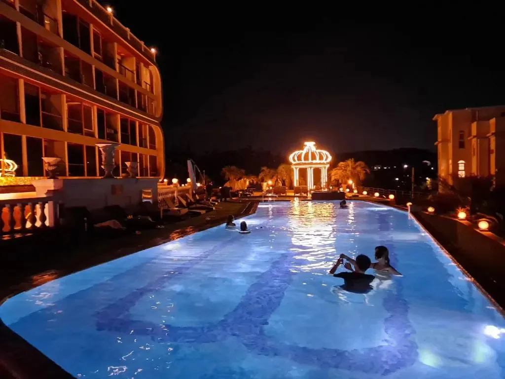 Une piscine illuminée au crépuscule avec des personnes se relaxant dans l'eau.
