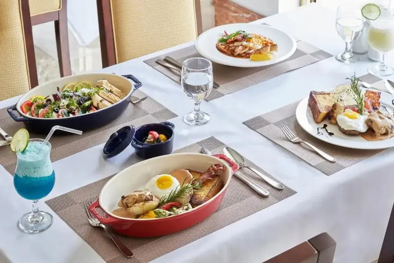 Une table est dressée avec plusieurs plats colorés et des boissons.