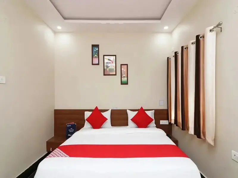 Une chambre lumineuse avec un grand lit recouvert d'une courtepointe rouge et de coussins.