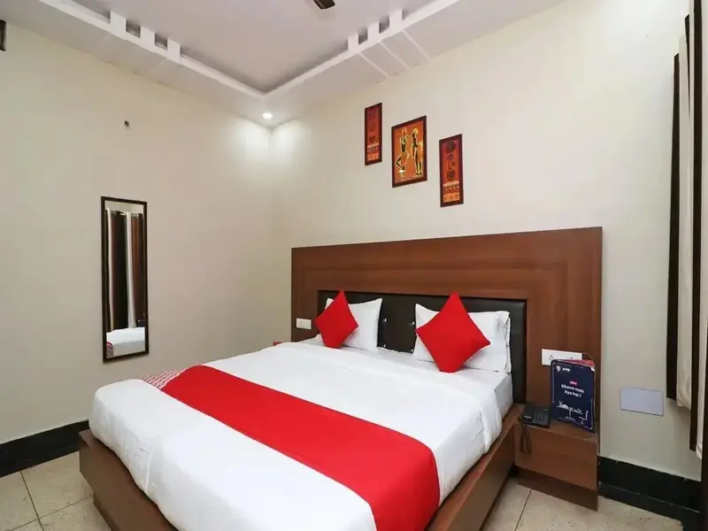 Une chambre lumineuse avec un grand lit recouvert d'une courtepointe rouge et de coussins.