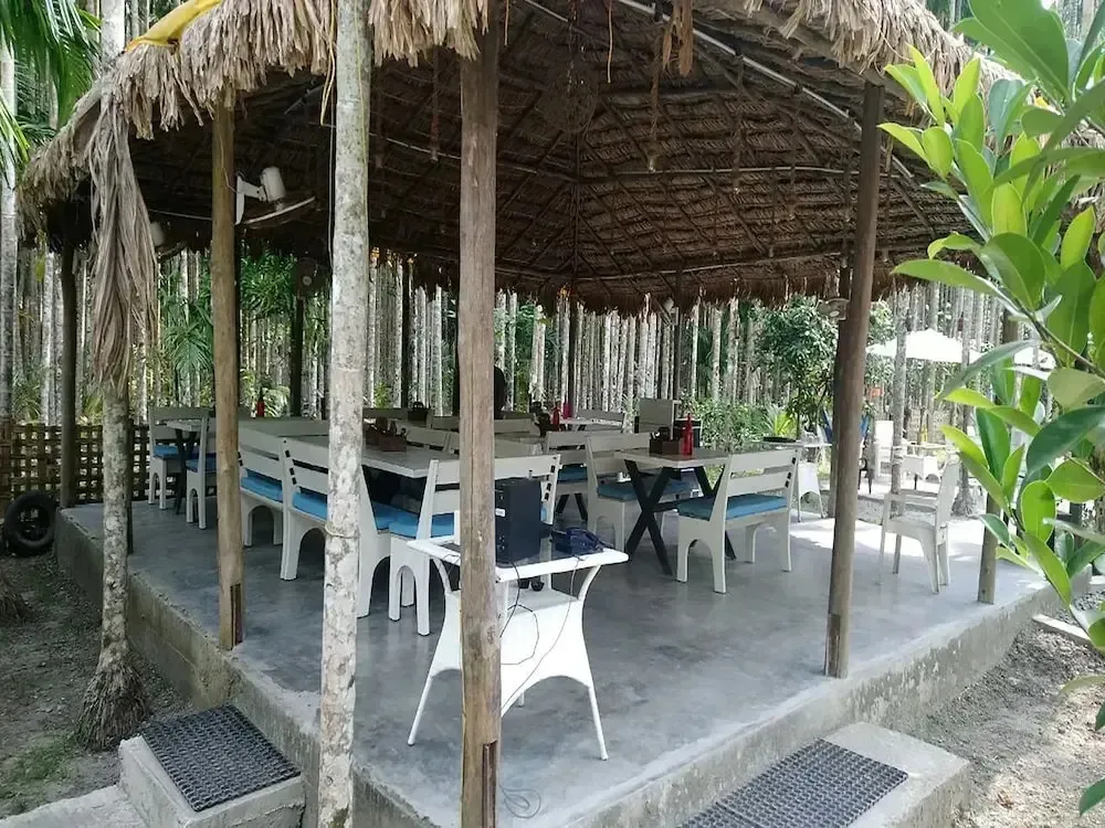 Une salle à manger extérieure abritée sous une toiture de chaume.