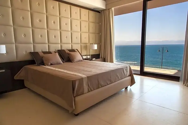 Une chambre lumineuse avec un grand lit face à la mer.