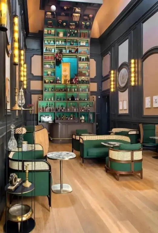 Un espace de détente intérieur avec des fauteuils verts et une bibliothèque décorative.