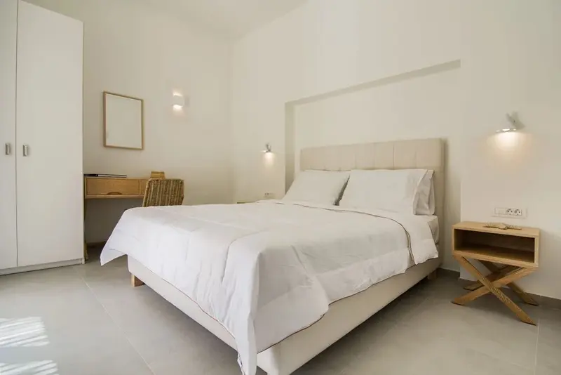 Une chambre lumineuse avec un grand lit recouvert de draps blancs.