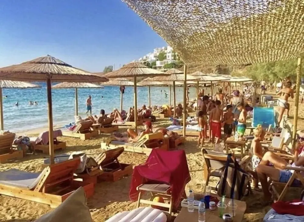 Transats et parasols ombragent une plage de sable fin bordée d'une mer turquoise.