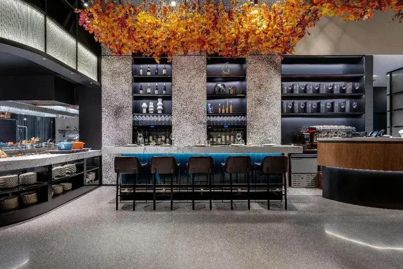 Un bar moderne avec des tabourets et une décoration florale suspendue.
