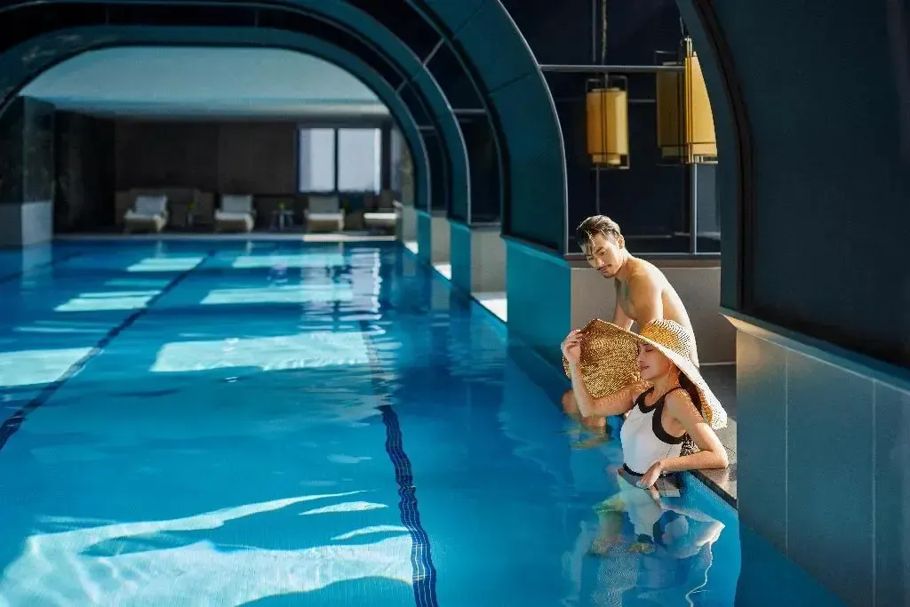 Un couple se détend au bord d'une piscine intérieure.