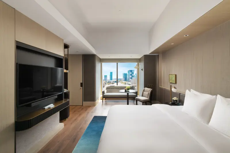 Une chambre lumineuse avec un grand lit et un coin salon près d'une fenêtre.